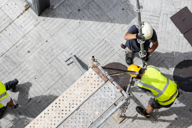 Construction workers assembling scaffolding structure on a job site viewed from above
